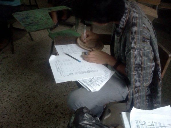 Tojin Benito, estudiante Poqomam escribiendo su texto en un plato redondo de cerámica.