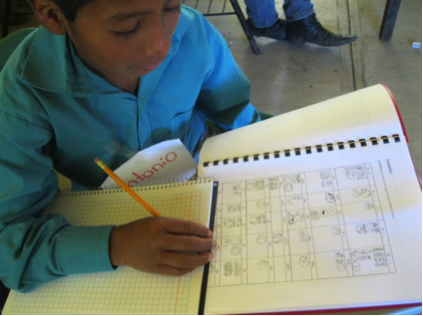 Antonio excitedly looking at the syllabary before beginning to write his name.