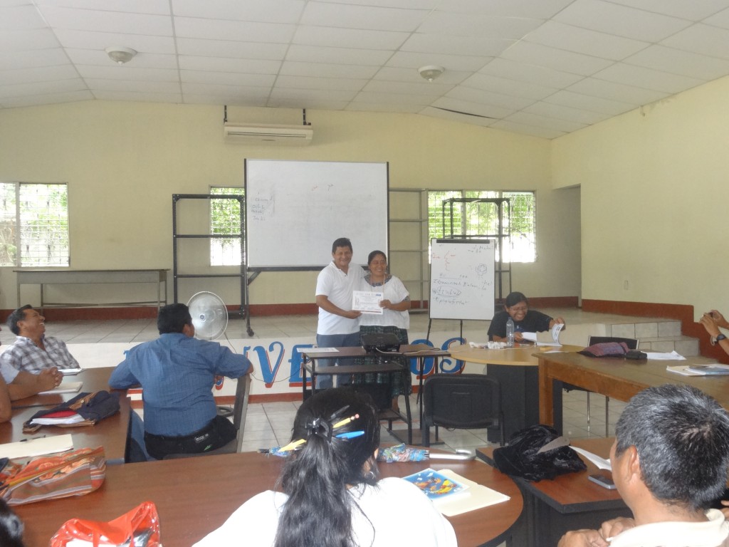 Romel Reyes, Director of Defensoría Q'eqchi', delivering a certificate of participation for one of the teachers.