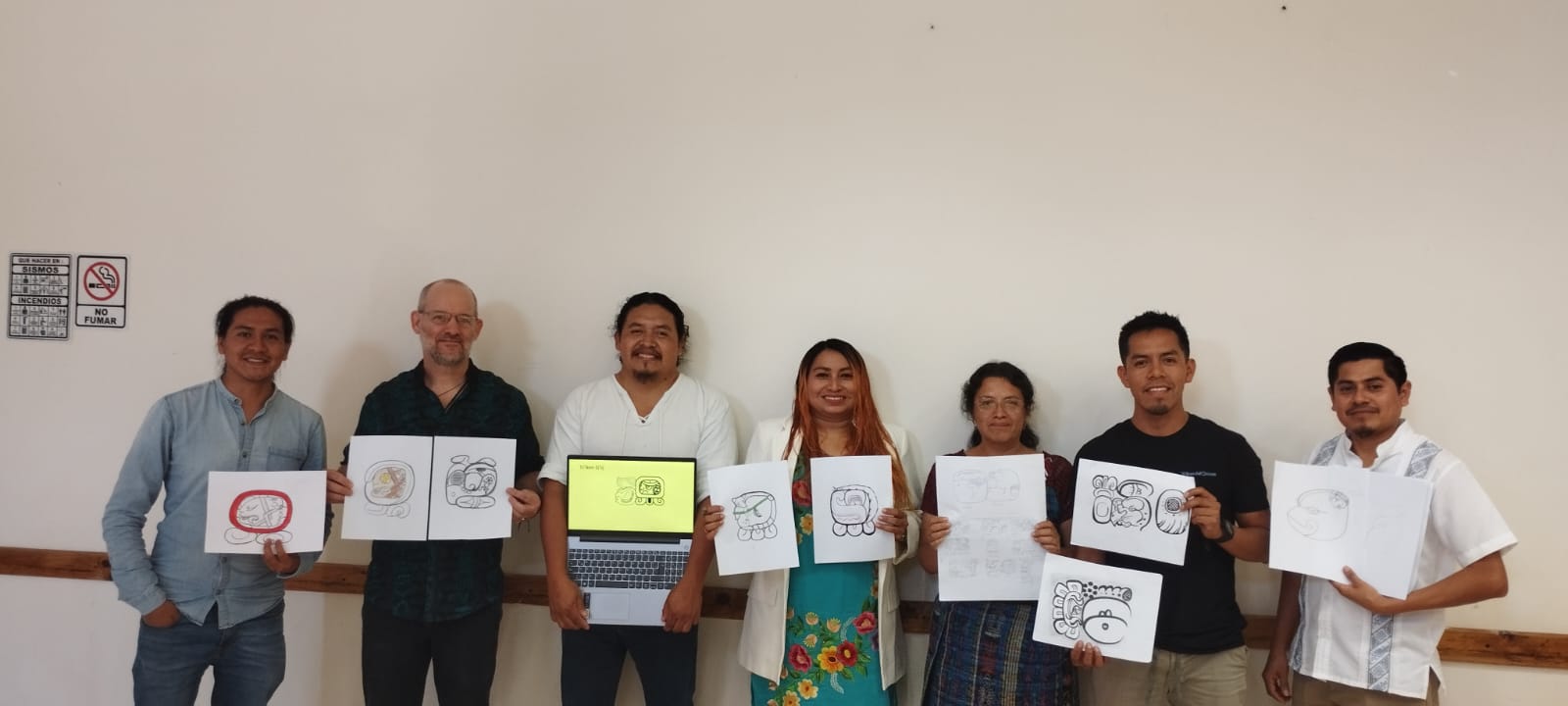 A group of people holding up drawings

Description automatically generated