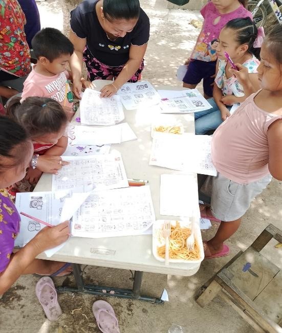 A group of children sitting around a table with paper

Description automatically generated
