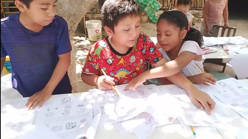 A group of children working on paper

Description automatically generated